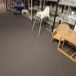Winkelvloer met diverse houten en witte stoelen in een kringloopwinkel