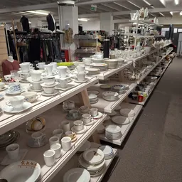 Vitrinekast met uitgestalde servies en kopjes in verschillende stijlen en kleuren