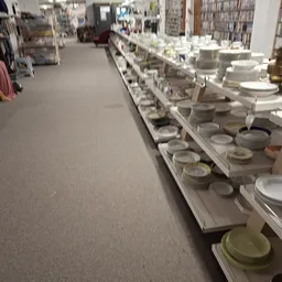 Stellingen met diverse serviesgoed en borden uitgestald in de winkel