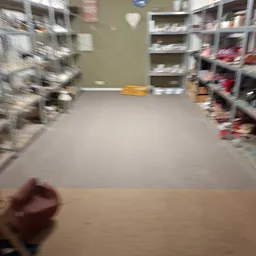 Winkelvloer van kringloopwinkel met stellingen aan zijkanten en gele waarschuwingsbord in het midden