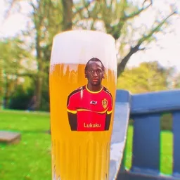 Bierglas met portretetiket van een voetballer, buiten in een tuin