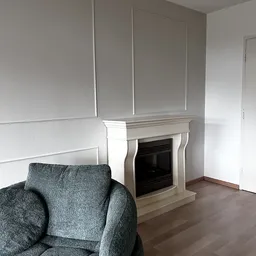 Grijze fauteuil en wit open haardkachel in woonkamerinterieur