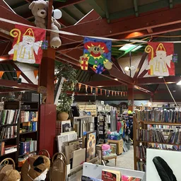 Binnenzicht van kringloopwinkel met boekenrekken, decoraties en verlichte houten balkenstructuur