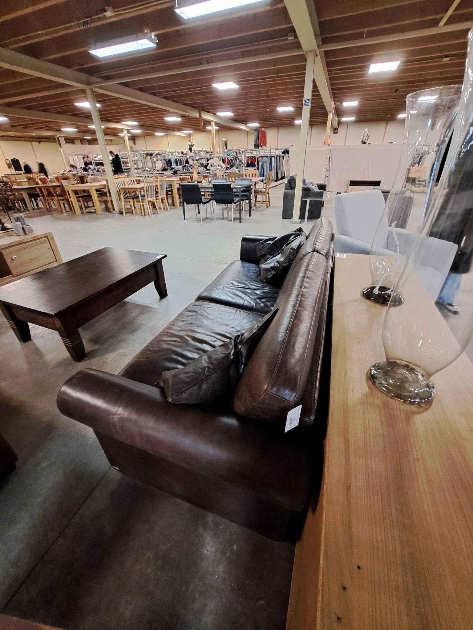 Winkelvloer met bruine leren bank, houten salontafel en diverse meubels en huishoudartikelen
