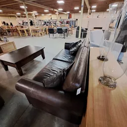 Winkelvloer met bruine leren bank, houten salontafel en diverse meubels en huishoudartikelen