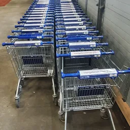 Rij van winkelwagens met blauwe mandje en naam Hergebruik Plus in kringloopwinkel