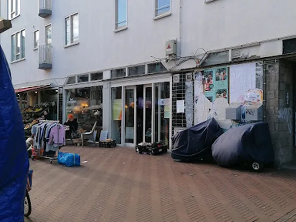 Voorgevel van kringloopwinkel met etalages, winkeldeur en opgestelde spullen op straat