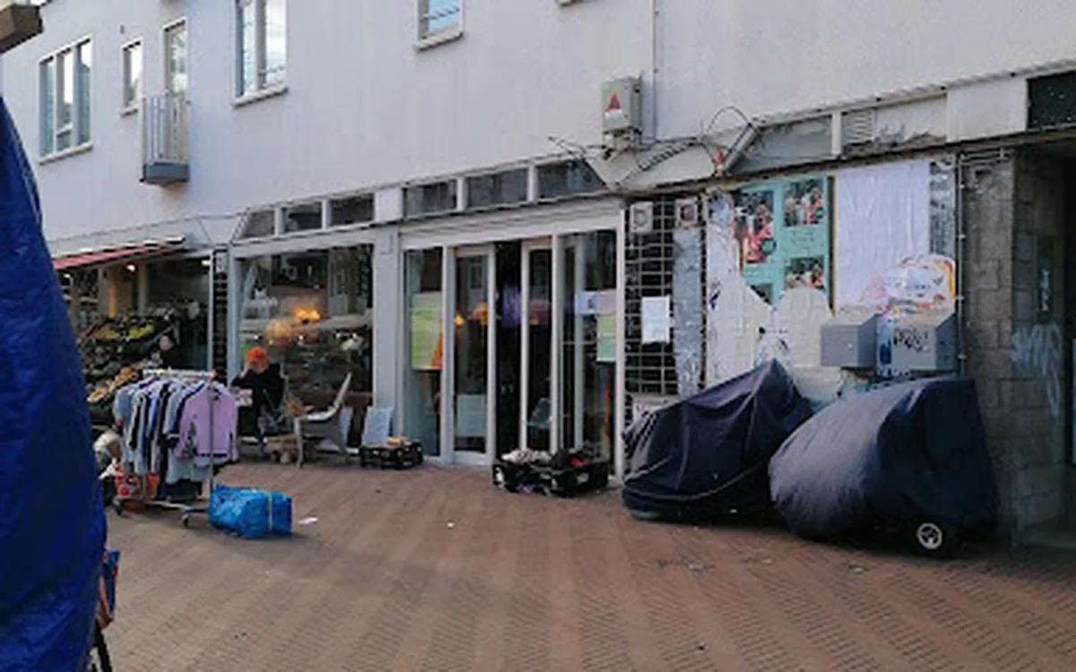 Voorgevel van kringloopwinkel met etalages, winkeldeur en opgestelde spullen op straat