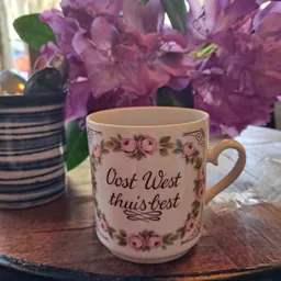 Crèmekleurige mok met roze bloemenpatroon en tekst 'Oost West thuis'best'
