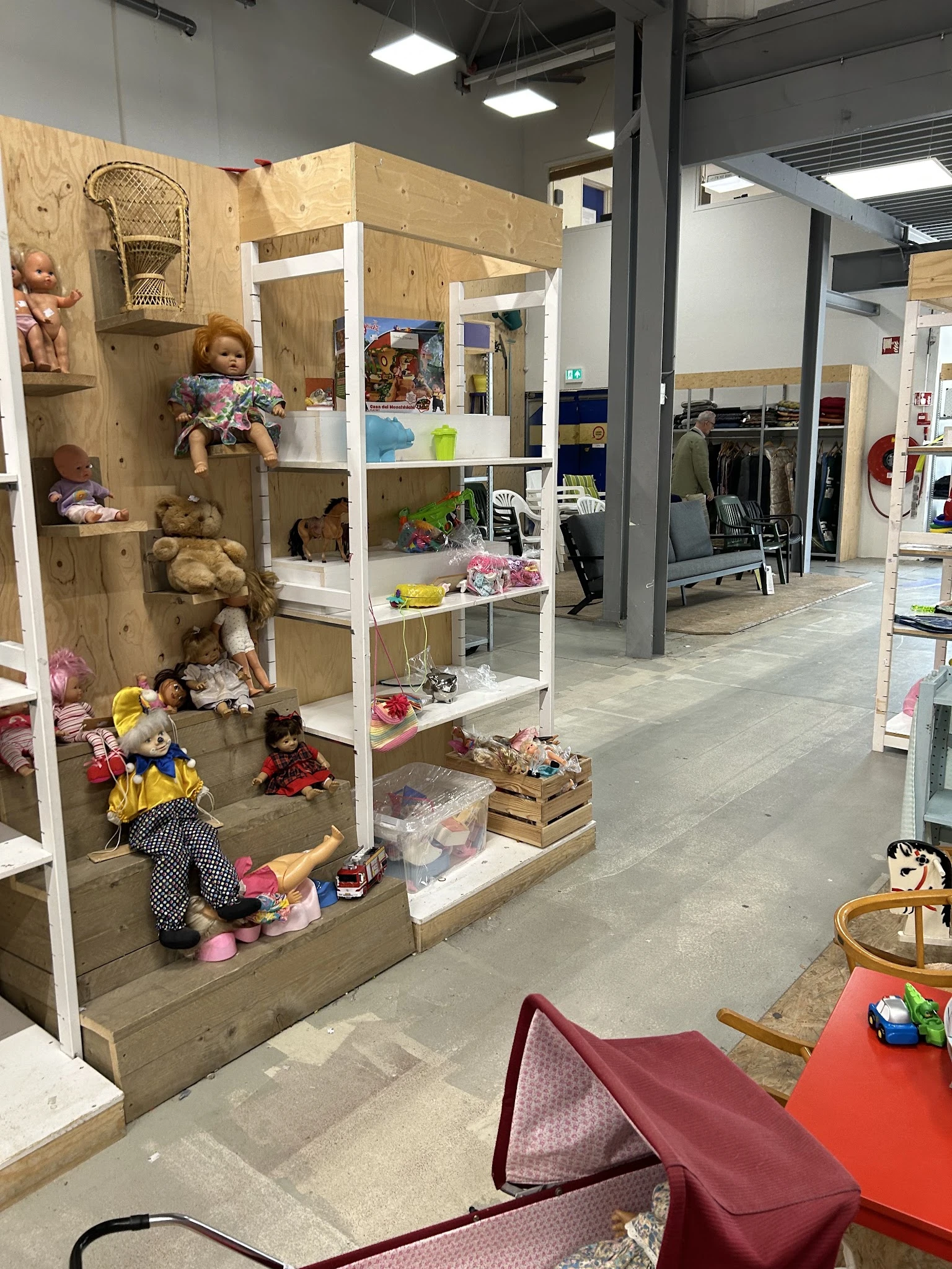 Winkelinterieur met stellingen vol speelgoed, poppen en andere artikelen, zicht op winkeloppervlak