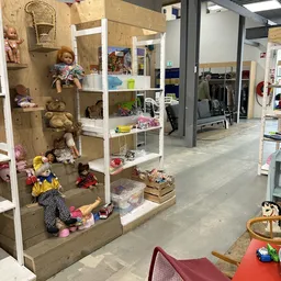 Winkelinterieur met stellingen vol speelgoed, poppen en andere artikelen, zicht op winkeloppervlak