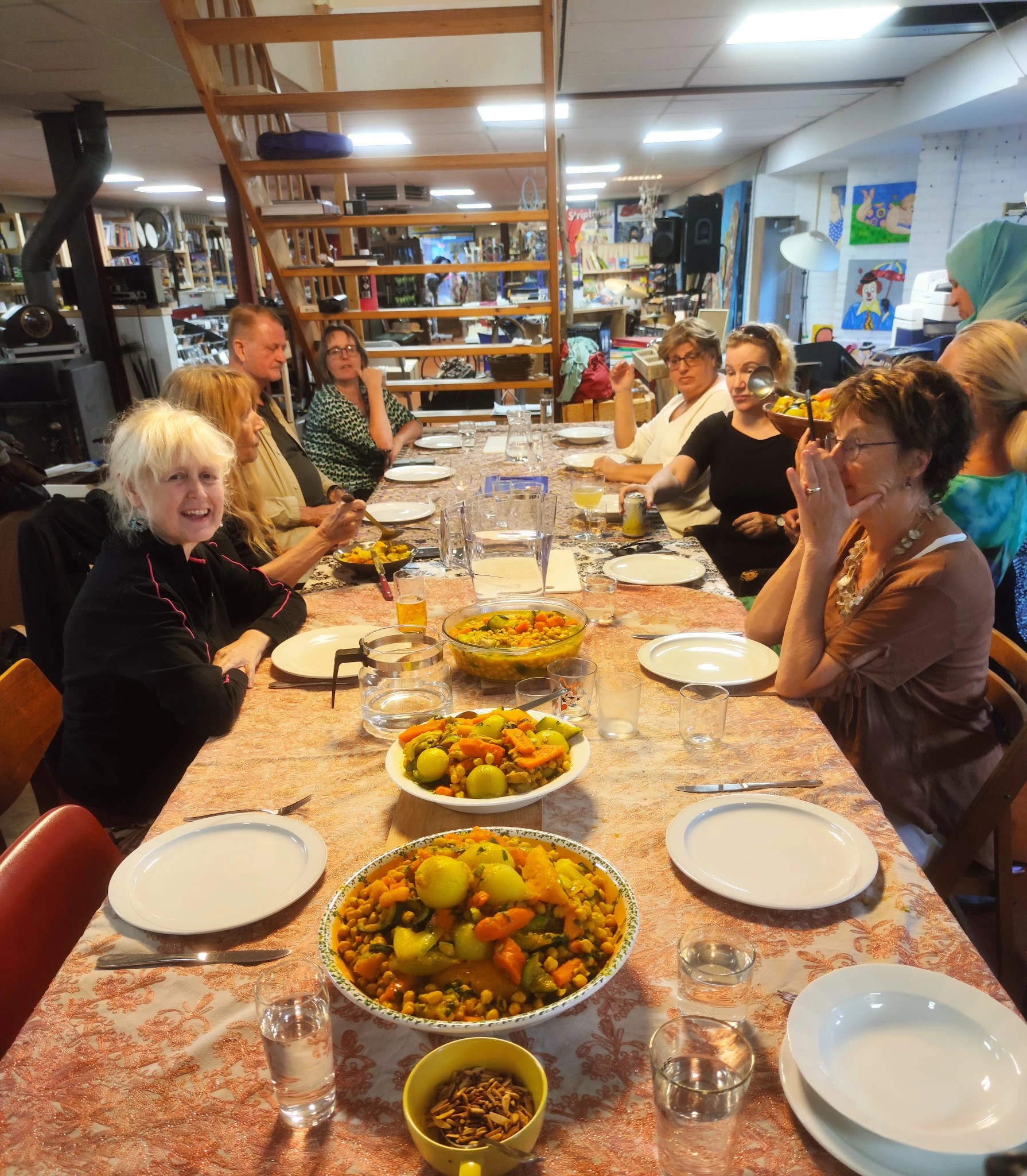 Groep mensen aan tafel met borden eten en glazen water tijdens een maaltijd in de winkel