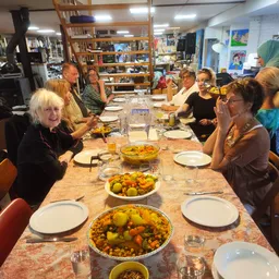 Groep mensen aan tafel met borden eten en glazen water tijdens een maaltijd in de winkel