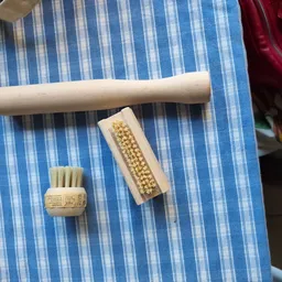 Drie houten schoonmaakborstels op een blauw-wit gestreepte doek