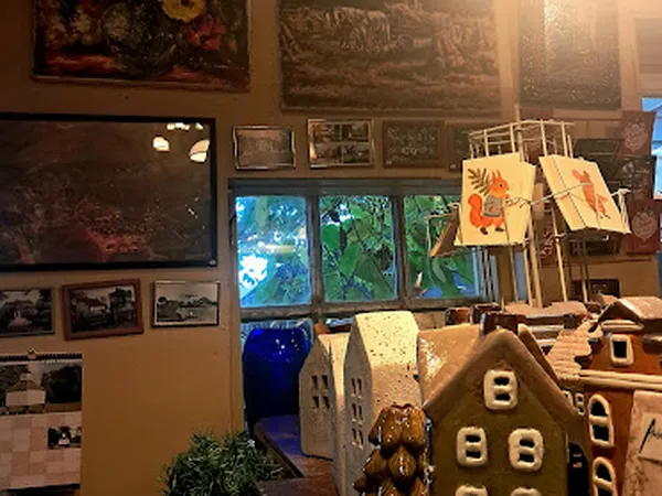 Winkelvloer met wanddecoratie, kunstwerken, speelgoedhuisjes en kleurrijke schilderijen op een drogingsrek