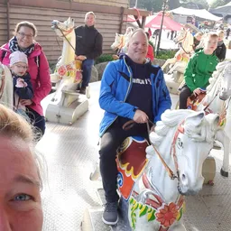 Bezoekers rijden op decoratieve draaimolens tijdens een evenement buiten de winkel