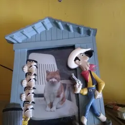 Speelgoedfiguur van een man met pistool naast een blauwe hutje met poppen