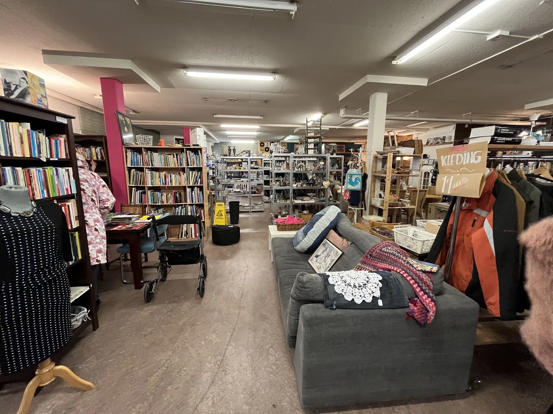Winkelvloer van kringloopwinkel met boekenkasten, kledingrekken, meubels en verschillende tweedehands artikelen