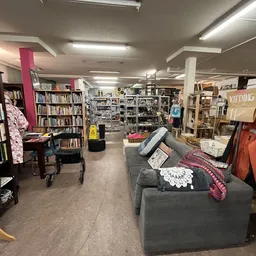 Winkelvloer van kringloopwinkel met boekenkasten, kledingrekken, meubels en verschillende tweedehands artikelen