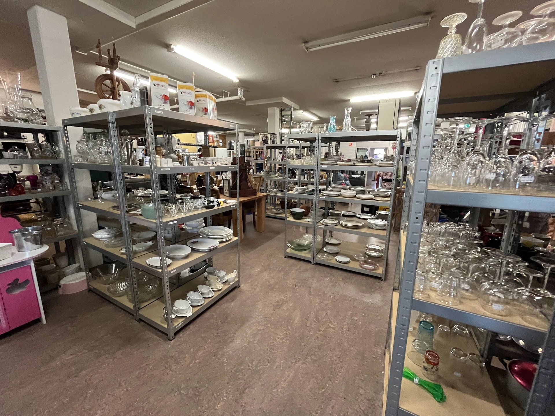 Winkelvloer met glazen vitrinekasten vol met serviesgoed en huishoudartikel