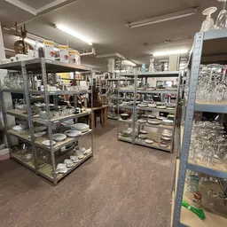 Winkelvloer met glazen vitrinekasten vol met serviesgoed en huishoudartikel