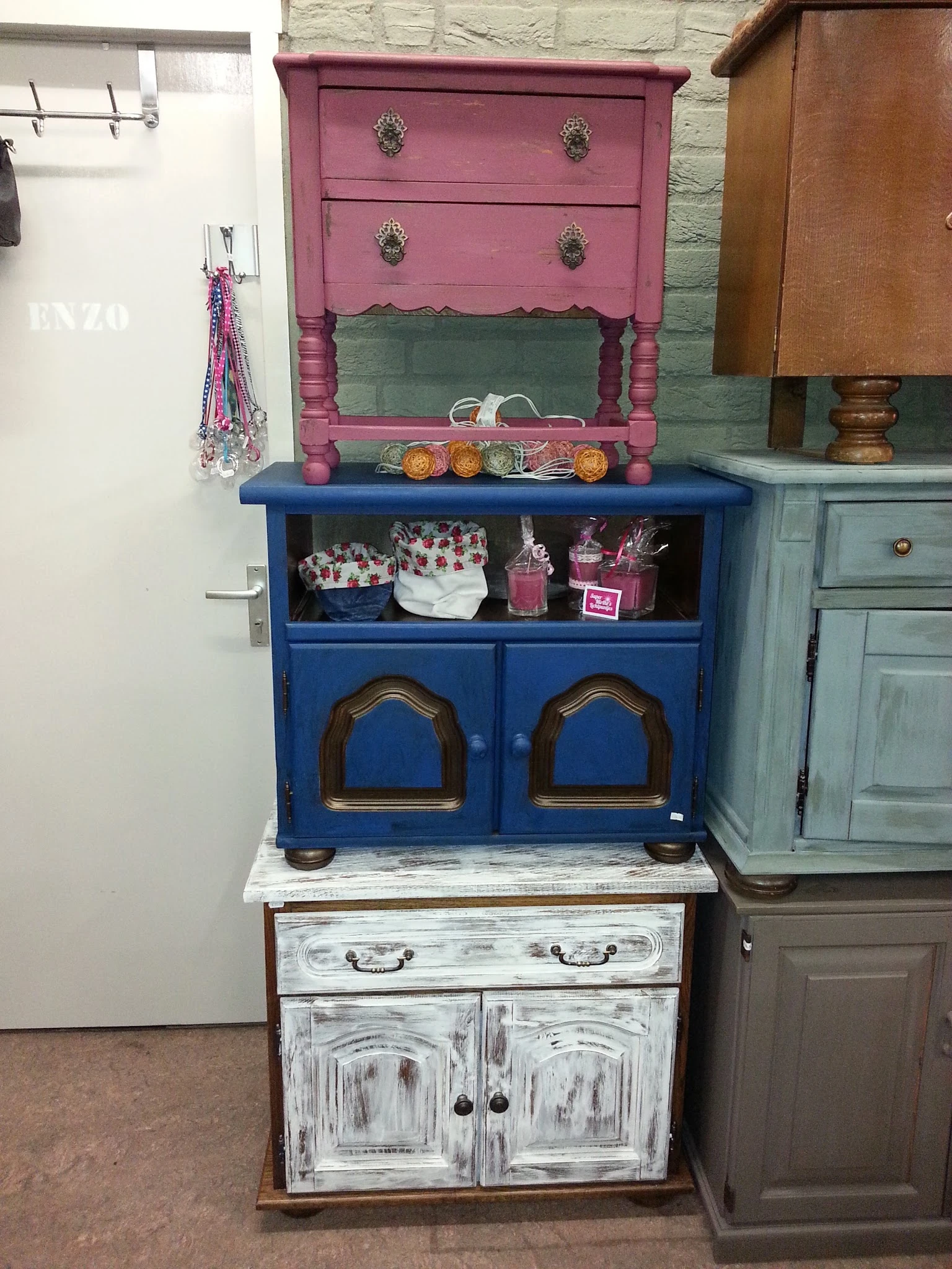 Blauwe vintage kast met houten details en open stellingvak, gevuld met decoratieve spullen en dozen