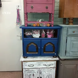 Blauwe vintage kast met houten details en open stellingvak, gevuld met decoratieve spullen en dozen