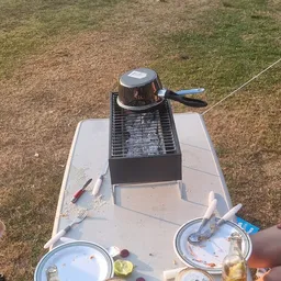 Barbecue en kookgerei op een witte tafel buiten op gras