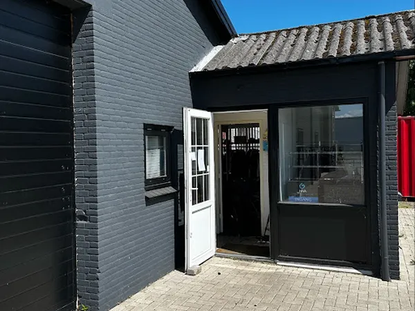 Voorkant van kringloopwinkel met zwarte bakstenen gevel, witte deur en grote ramen