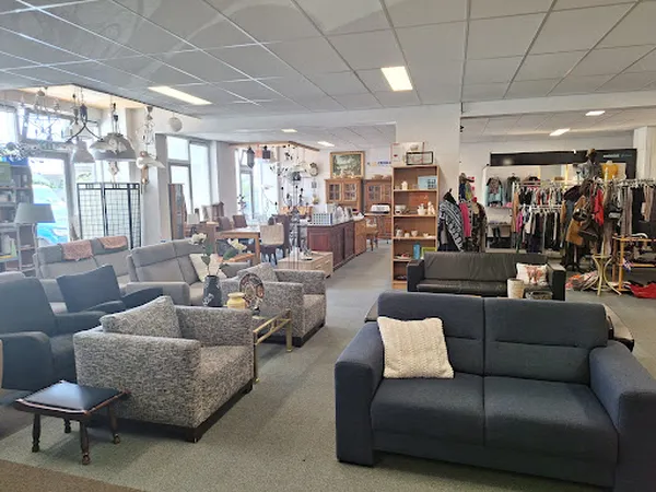 Winkelvloer met zitmeubels, kleding aan rekken en diversen inrichting in kringloopwinkel