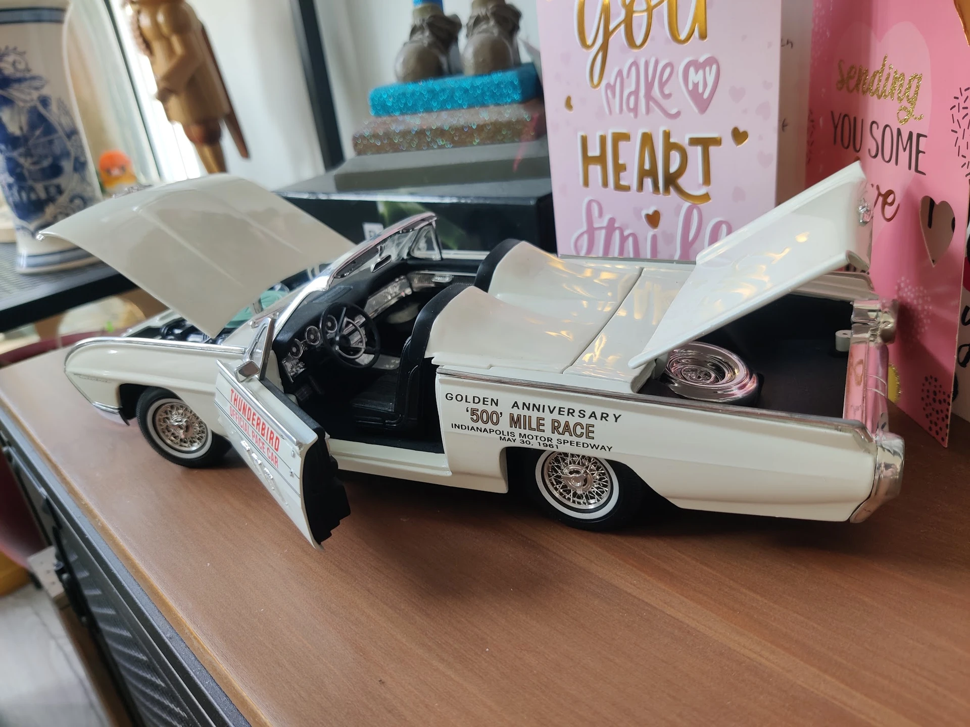 Wit modelauto'tje van een klassieke Amerikaanse auto met openstaande deuren op een houten oppervlak