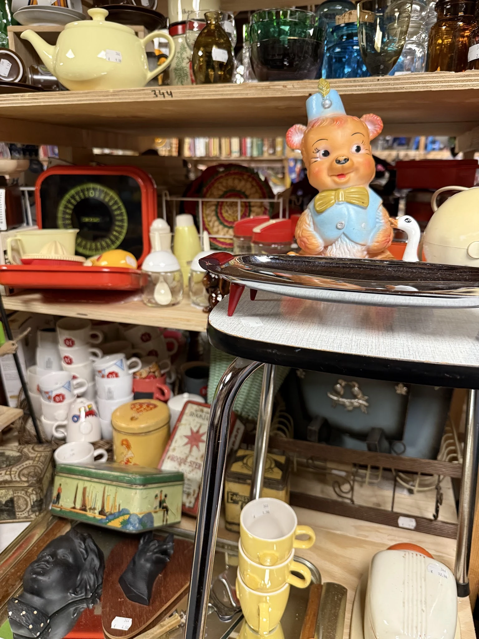 Diverse vintage en retro spullen uitgestald: keramische potten, vintage schalen, servies en decoratieve beeldjes