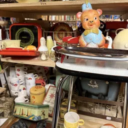 Diverse vintage en retro spullen uitgestald: keramische potten, vintage schalen, servies en decoratieve beeldjes