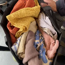 Diverse tweedehands textiel en stoffen in een zwarte tas