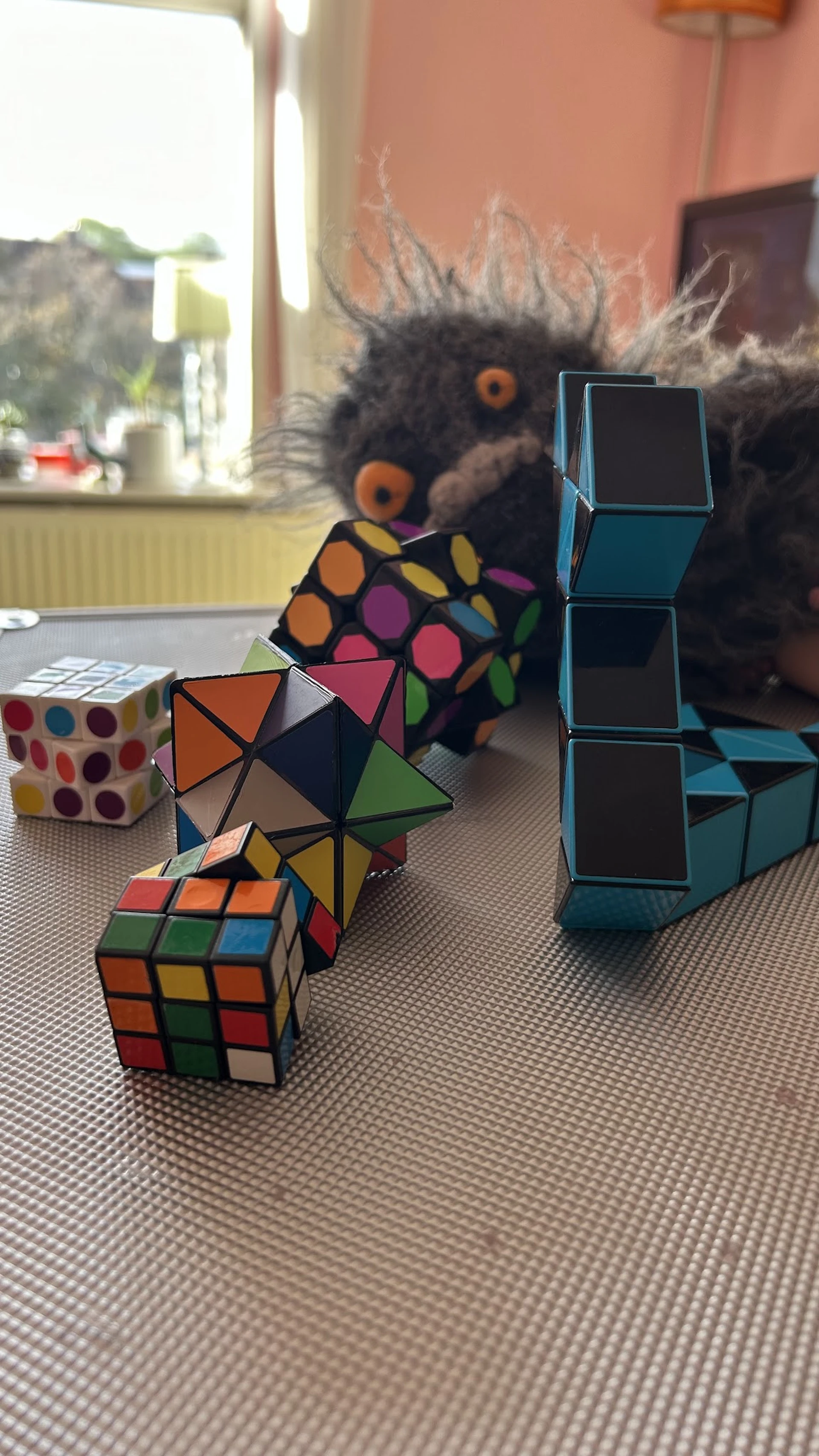 Verschillende puzzels en speelgoed op tafel: Rubik's cubes, pyramidepuzzels en andere kleurrijke breinbrekers