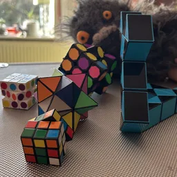 Verschillende puzzels en speelgoed op tafel: Rubik's cubes, pyramidepuzzels en andere kleurrijke breinbrekers