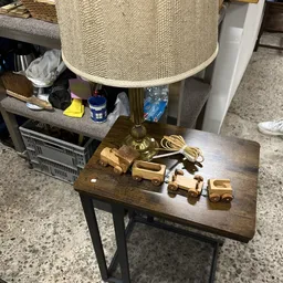Houten speelgoedauto's en vrachtwagens op een donkerhouten tafel naast een tafellamp