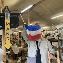 Persoon in winkel houdt Franse vlag omhoog voor gezicht