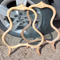 Houten sidetable of krukje met golvende randen tegen autowiel op parkeerplaats