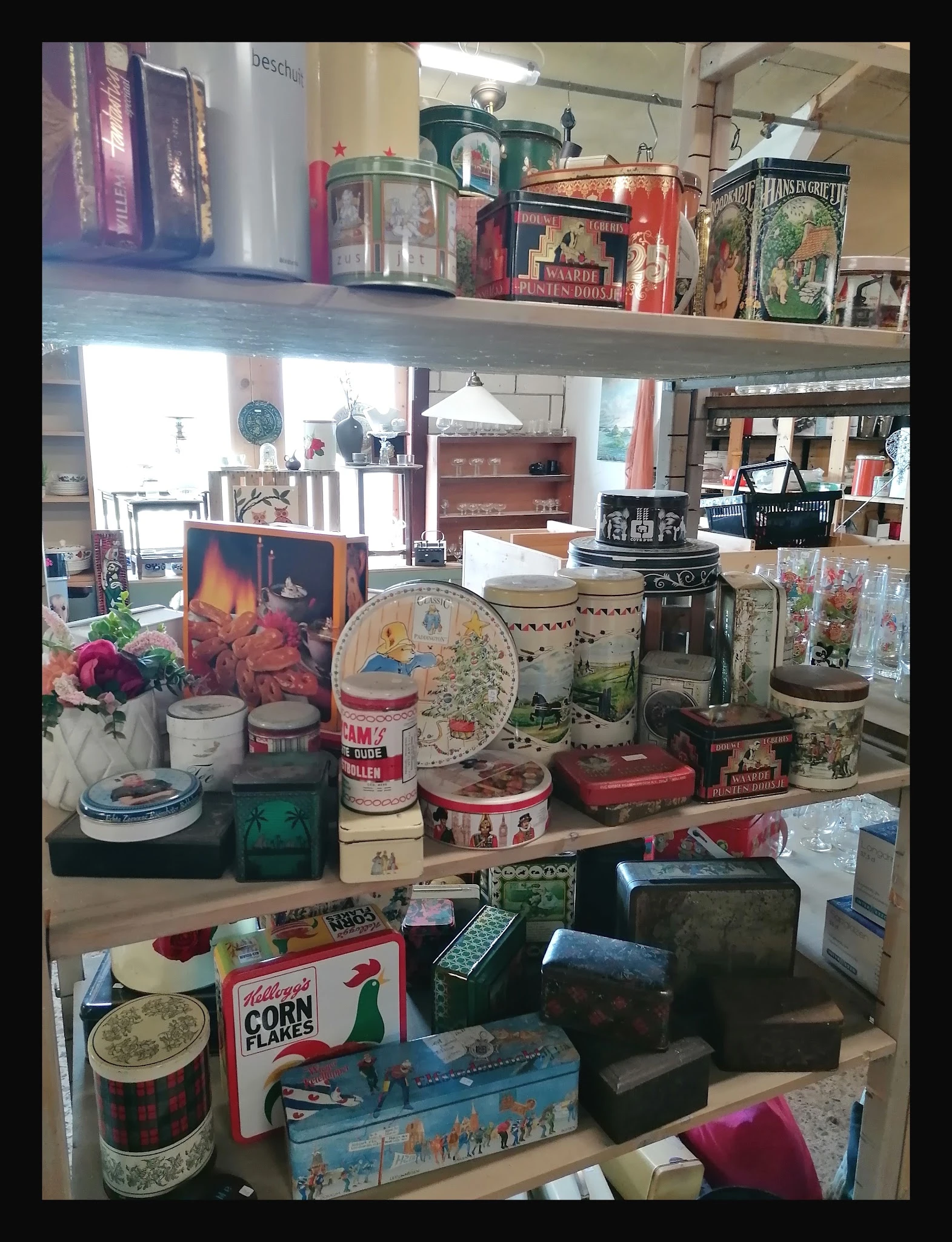 Vitrine met diverse huishoudelijke artikelen: bloemen, dozen, serviesgoed, decoratie en gebruiksvoorwerpen