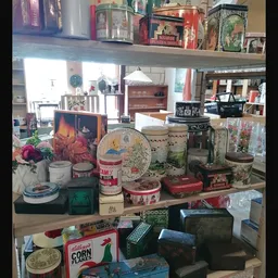 Vitrine met diverse huishoudelijke artikelen: bloemen, dozen, serviesgoed, decoratie en gebruiksvoorwerpen