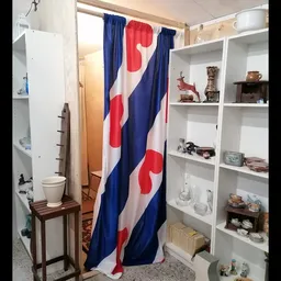 Winkelinterieur met witte stellingen, inboedelspullen en Nederlandse vlag als gordijn