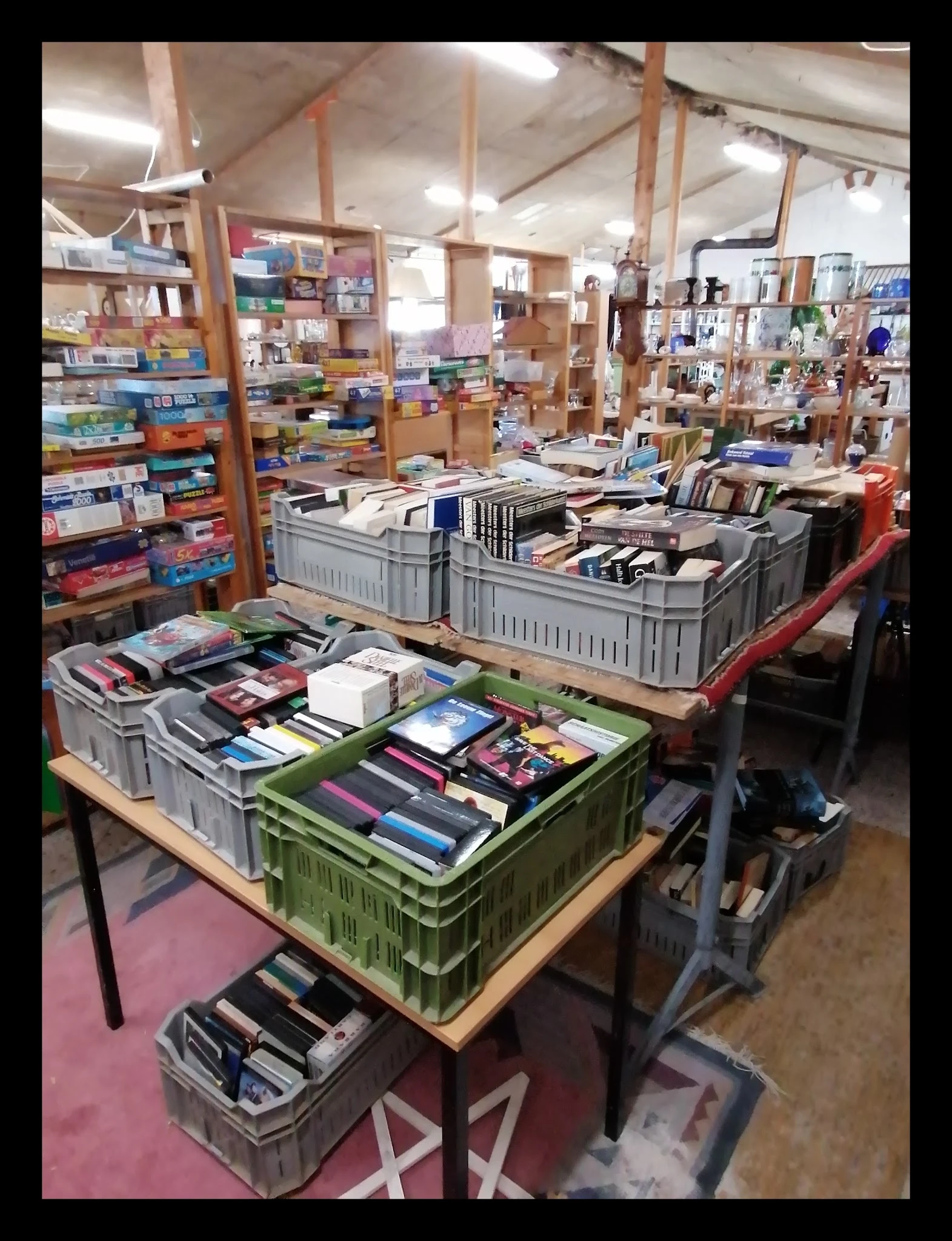 Plastic kratten met boeken op tafels in de winkel, stellingen met diverse artikelen op de achtergrond