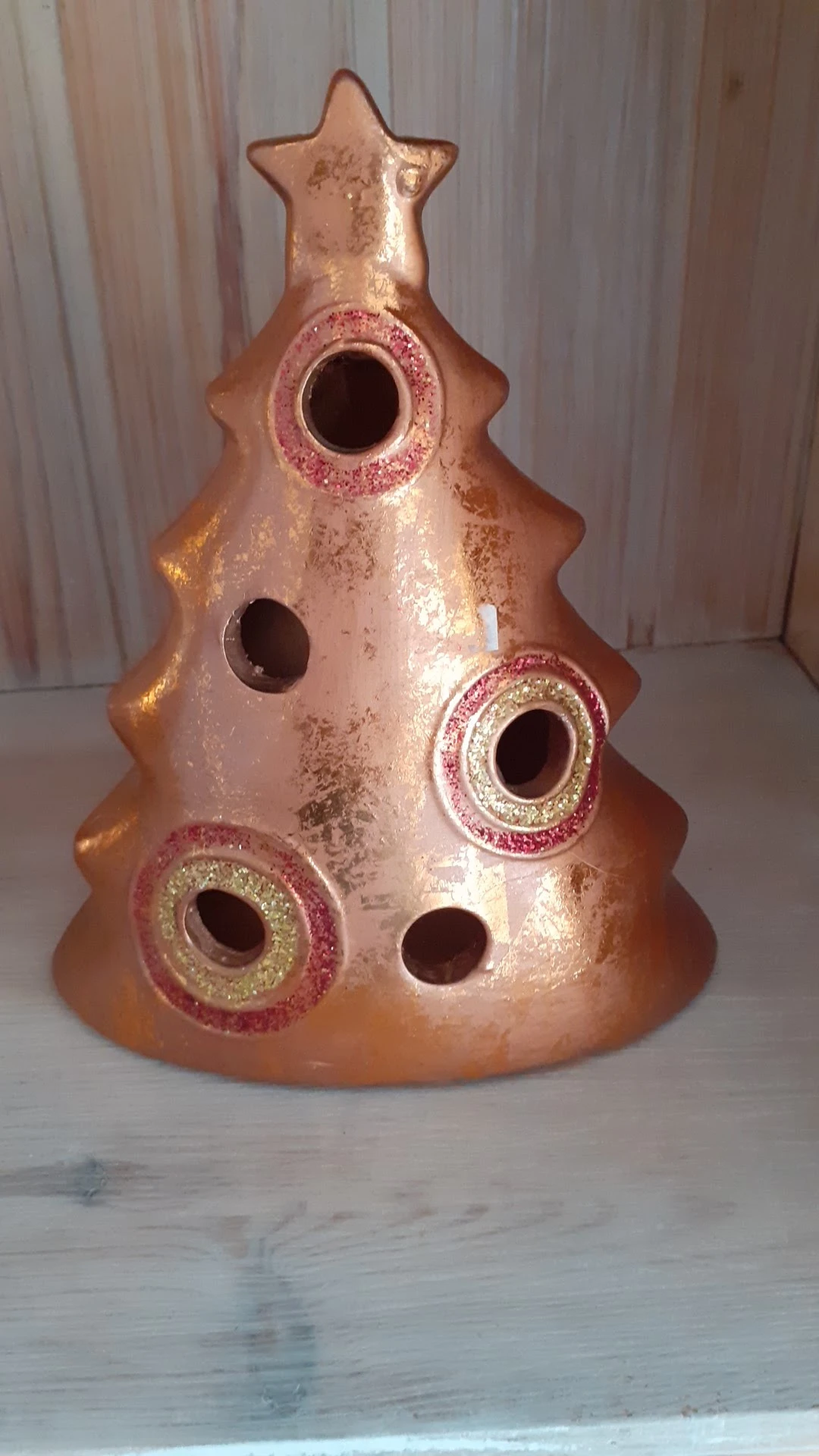 Close-up van een decoratieve keramische vogelverschrikker in roze en goud met glitterafwerking
