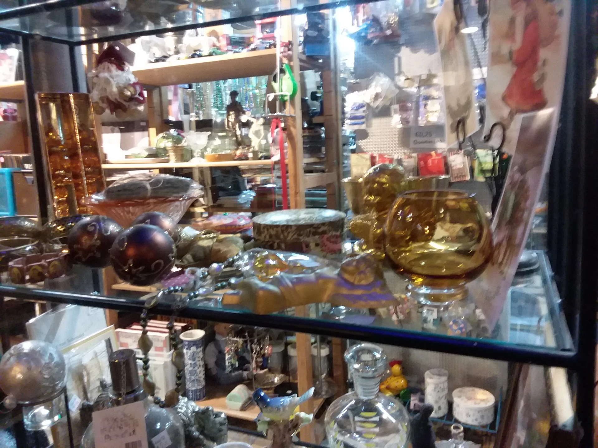 Glazen vitrinekast met decoratieve items zoals gouden beelden, glazen bollen en diversen huisraad