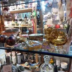 Glazen vitrinekast met decoratieve items zoals gouden beelden, glazen bollen en diversen huisraad