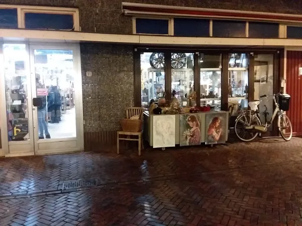 Winkelgevel met etalage, ingang en uitgestalde tweedehandsartikelen waaronder fiets en meubels