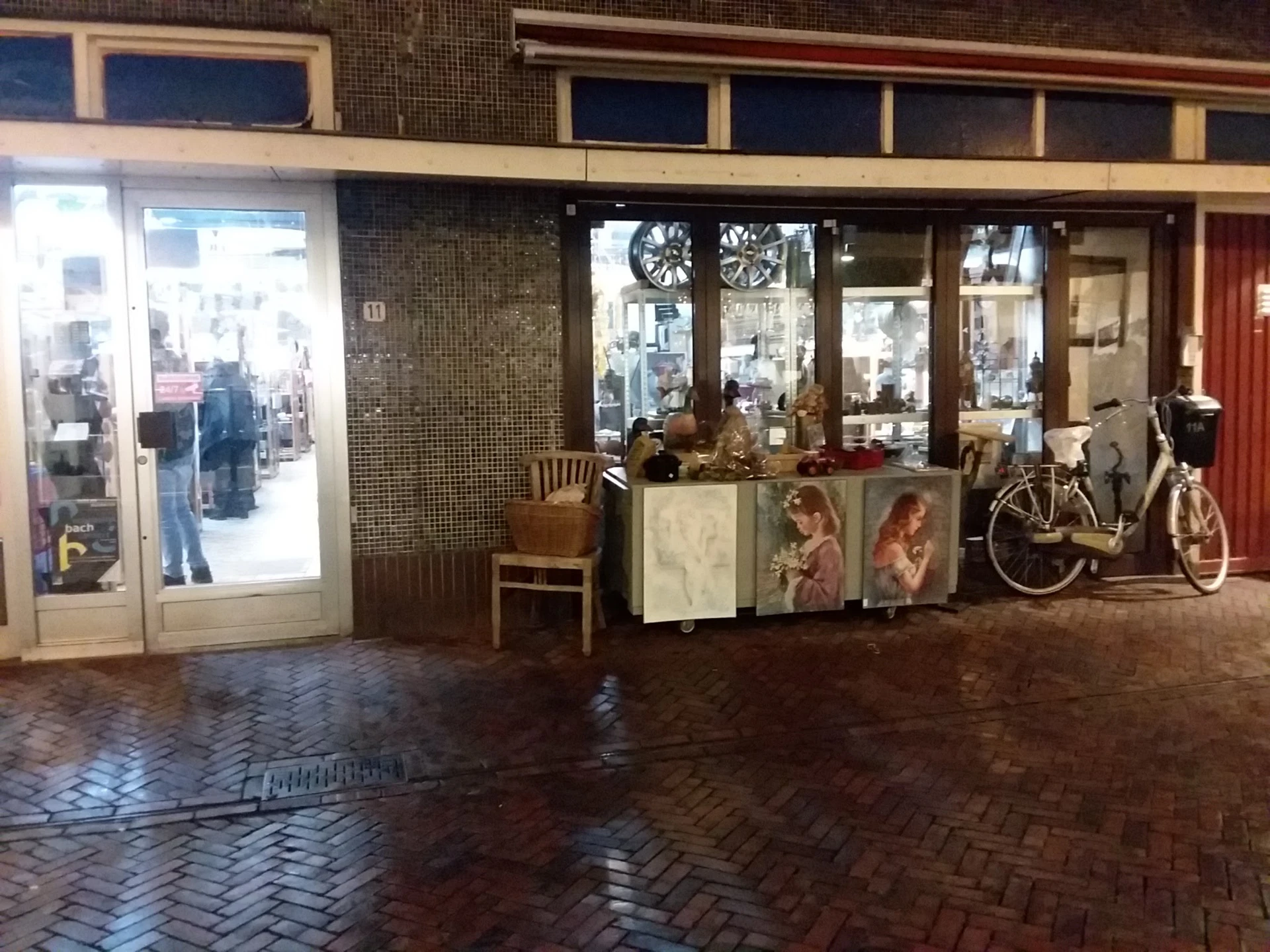 Winkelgevel met etalage, ingang en uitgestalde tweedehandsartikelen waaronder fiets en meubels