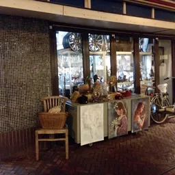 Winkelinterieur met uitgestalde meubels, decoraties en een fiets bij de etalage
