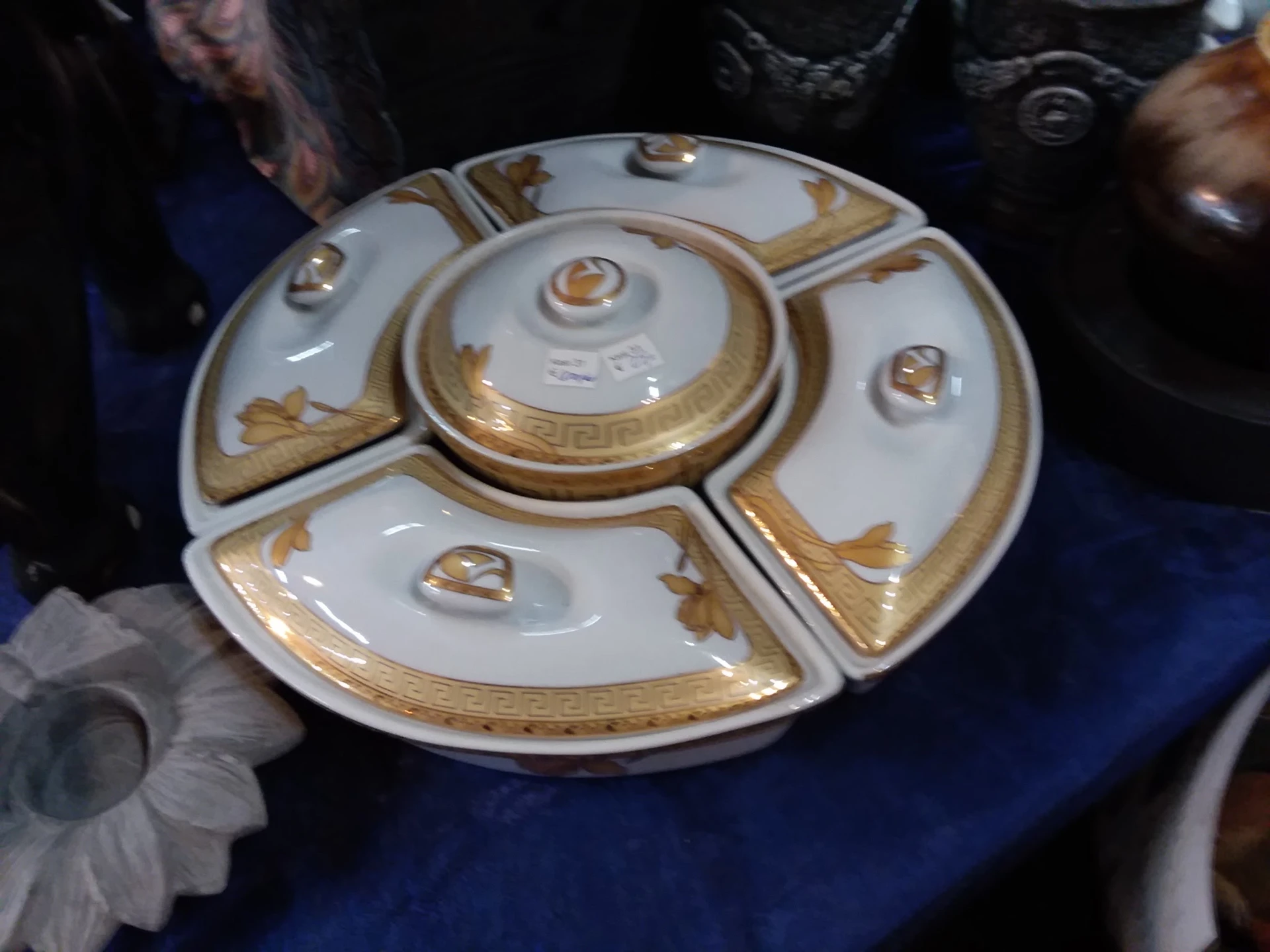 Decoratief porseleinen servies met goudkleurige versiering, bestaande uit een centrale schaal met vier uitstulpingen